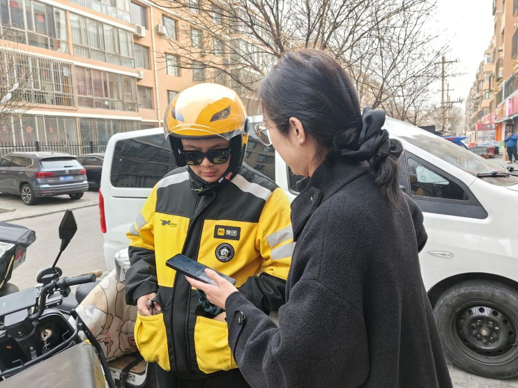 社區工作人員在外賣站點了解騎手需求并邀請騎手加入社區志愿服務群。青山區萬青路街道辦事處供圖